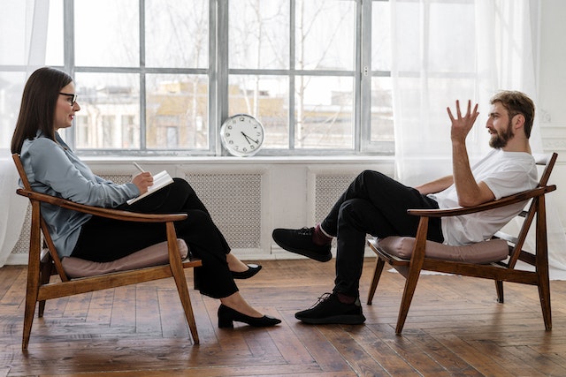 man and therapist sitting in chairs talking